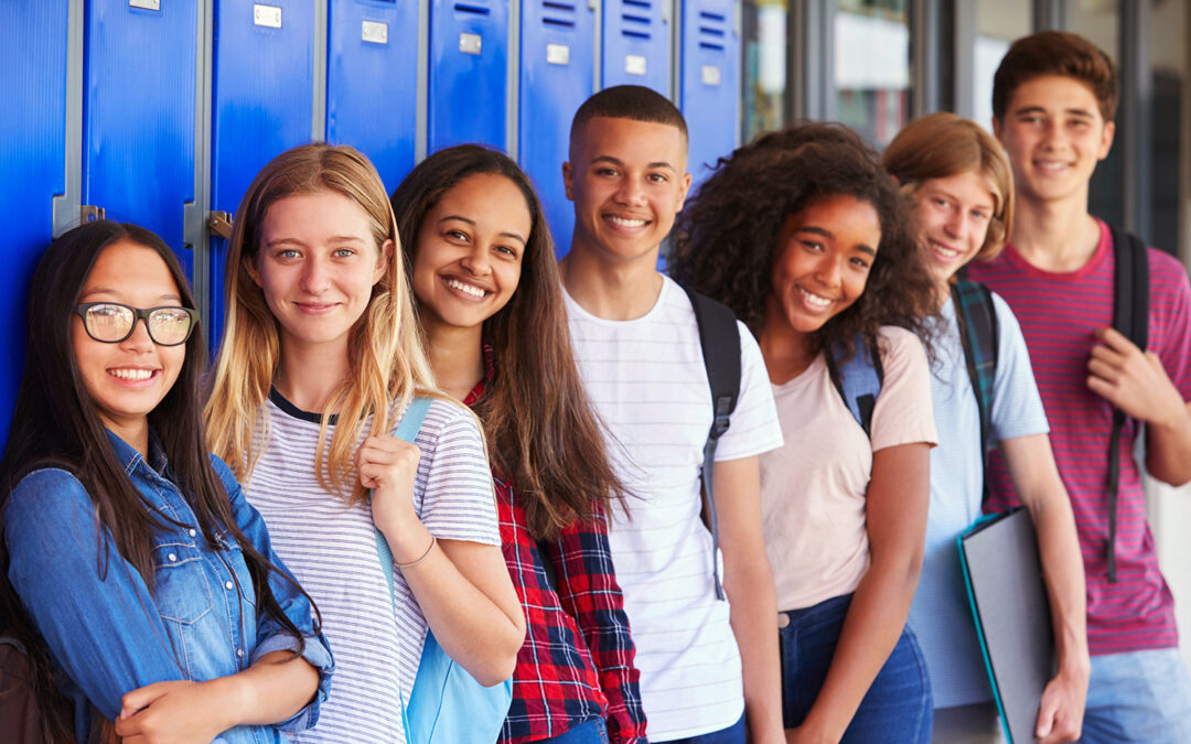 group of diverse teens standing in front of blue lockers