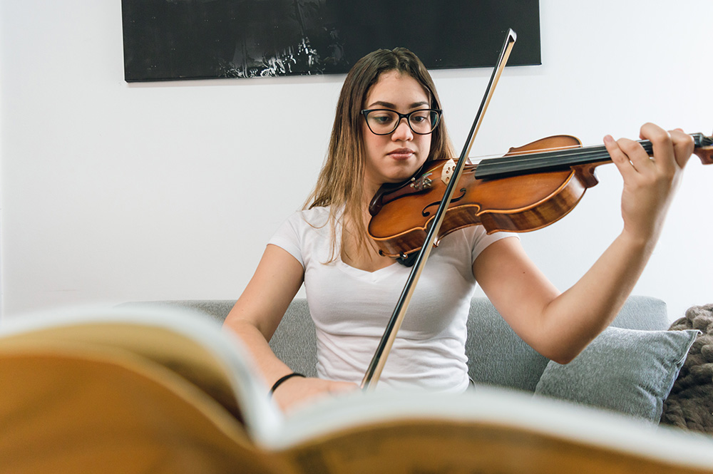 Teen girl practicing violin indoors